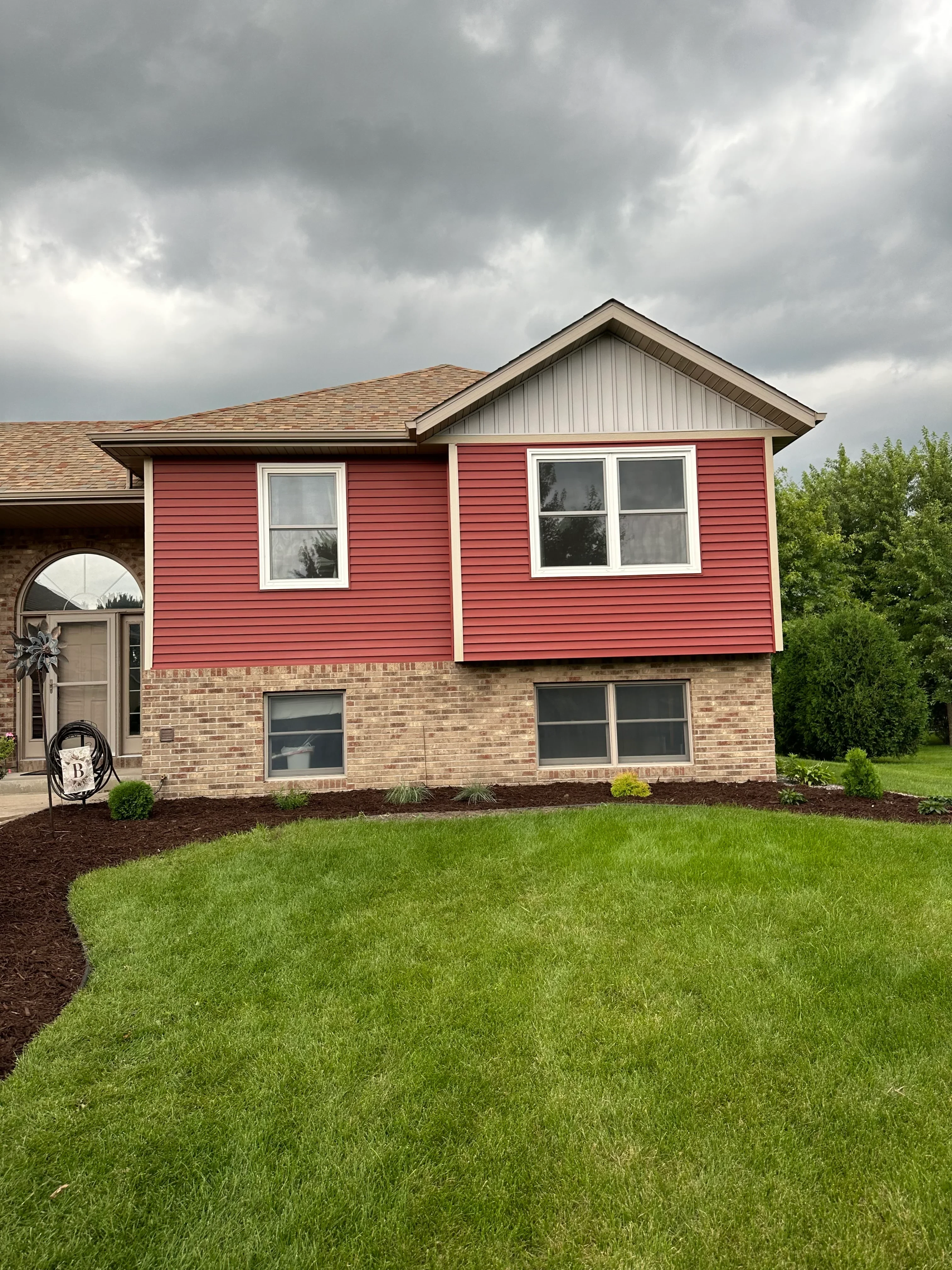 Newly installed residential lawn with mulch beds, mature trees, and professional landscape grading