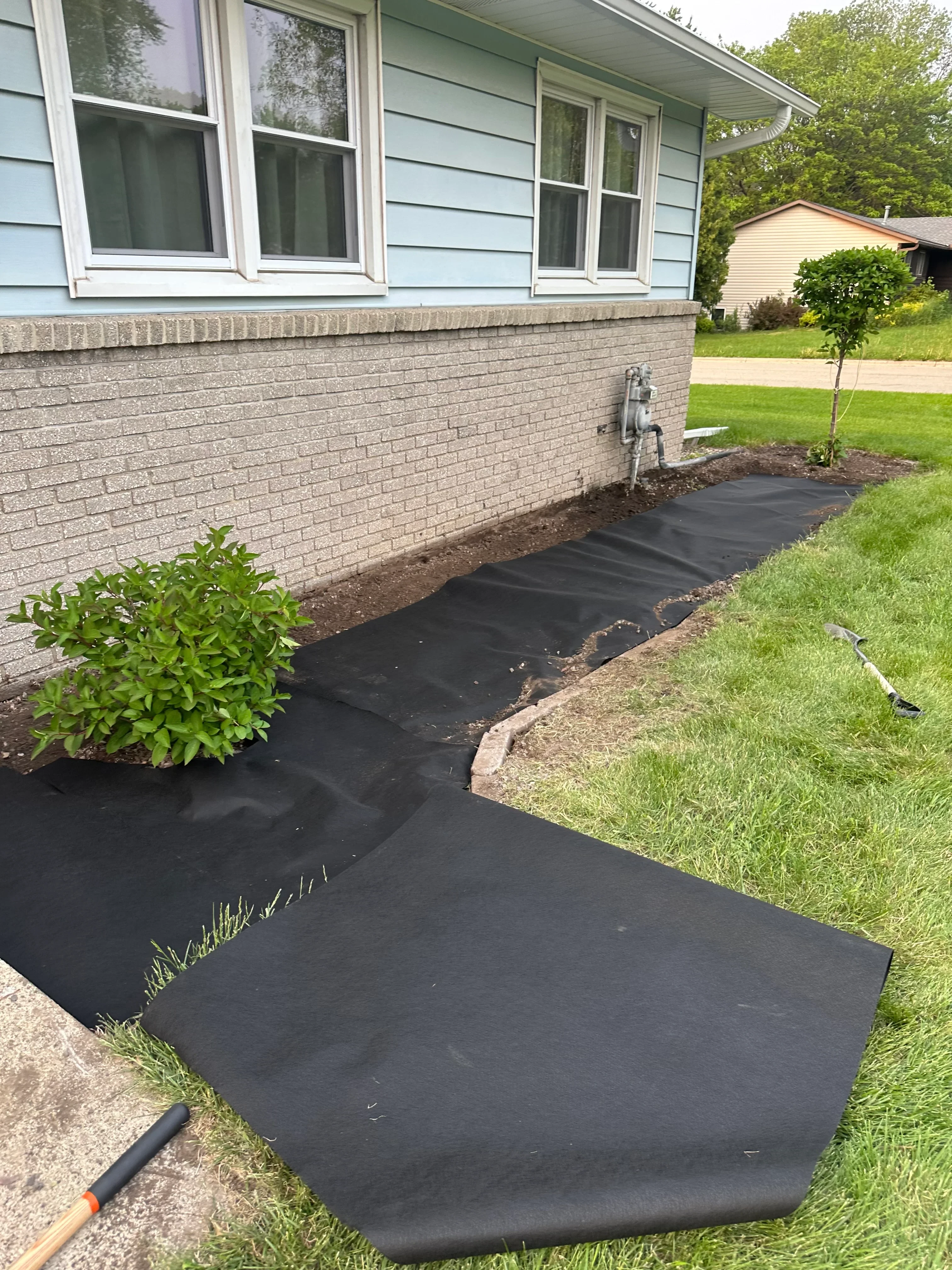Black landscape fabric installed on graded slope with proper drainage setup and soil preparation