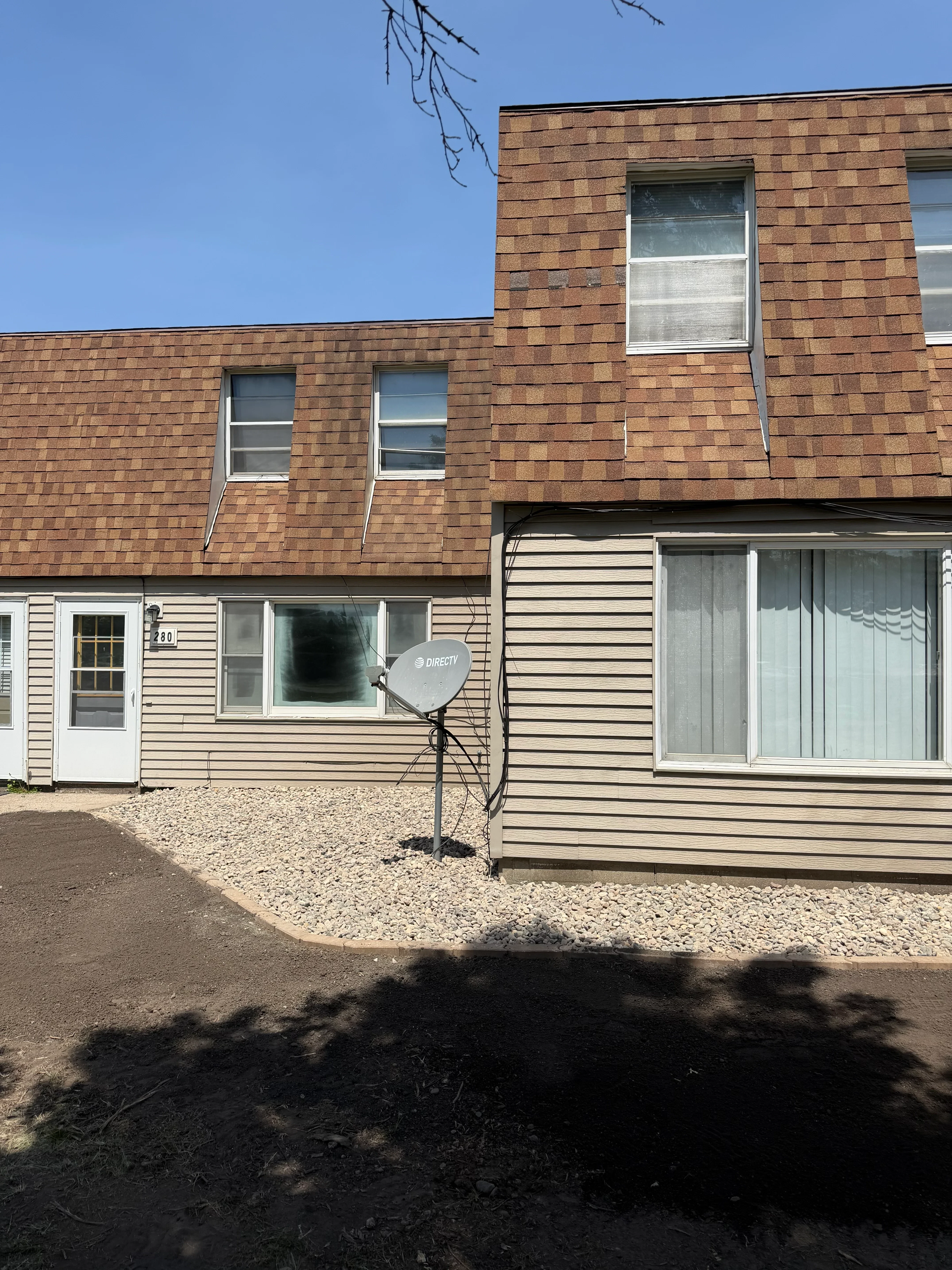 Brick and corrugated metal siding on residential building with new windows and graded foundation area
