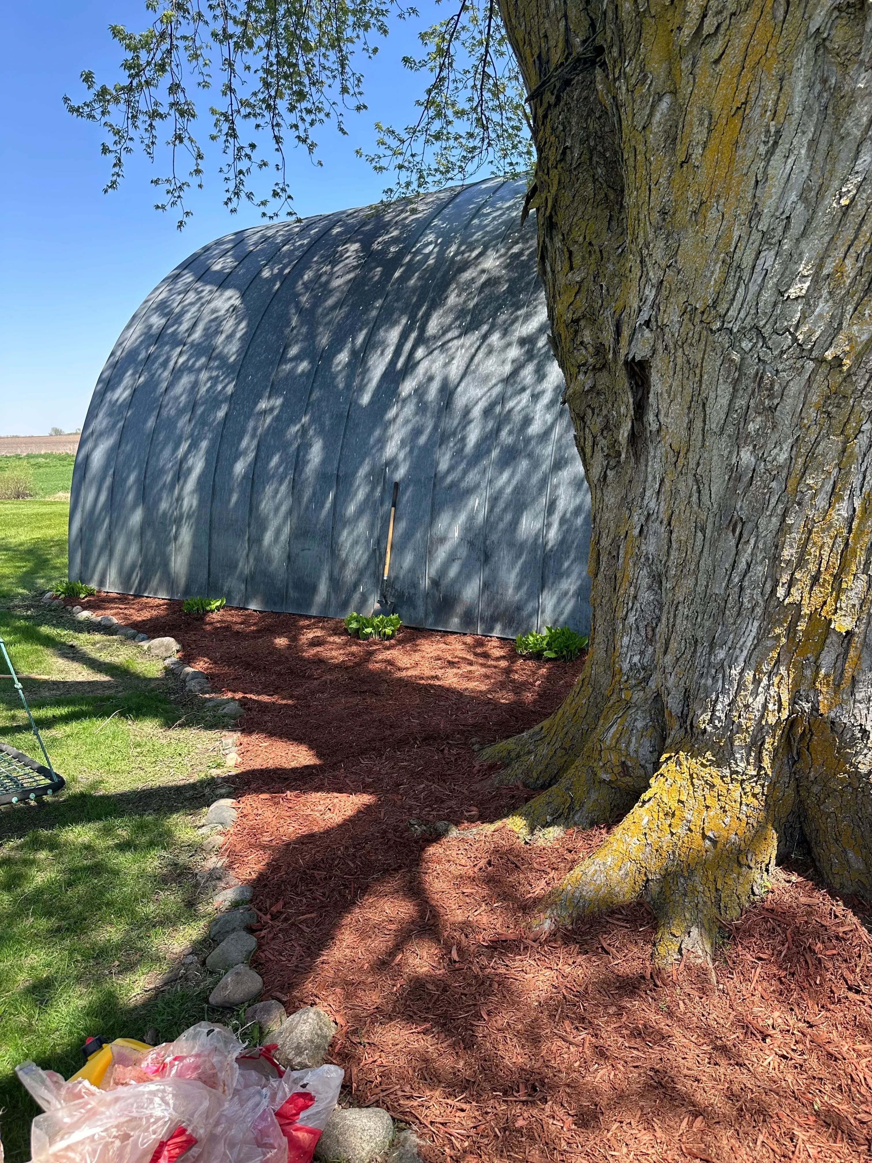 Historic stone structure with slate masonry, moss-covered surfaces, and flowering perennials at base