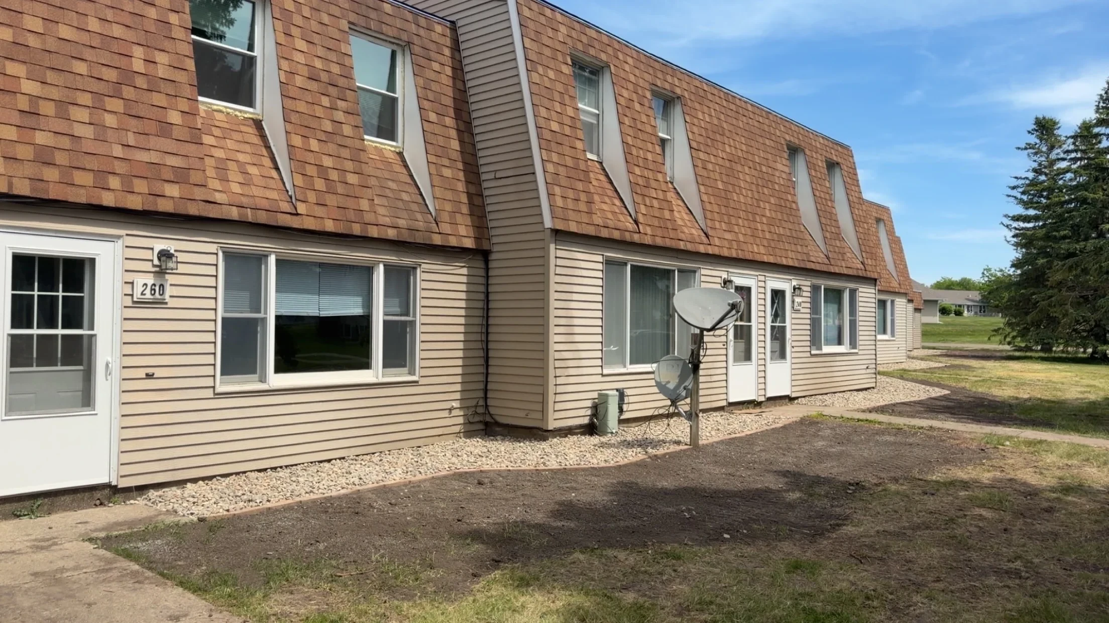Graded lawn with landscape plantings and drainage around brick residential home