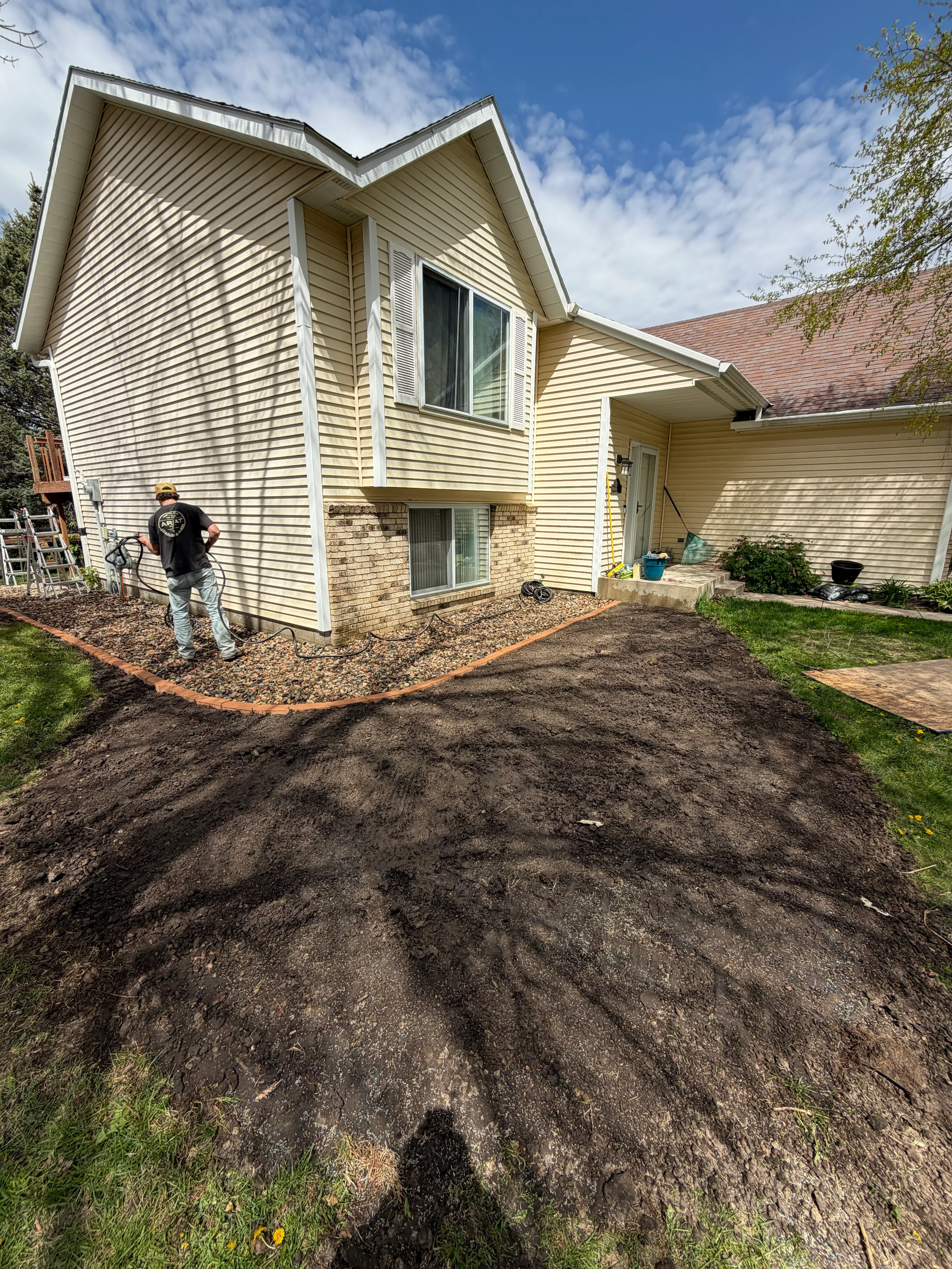 Graded residential lot with sloped earthwork adjacent to metal-sided home