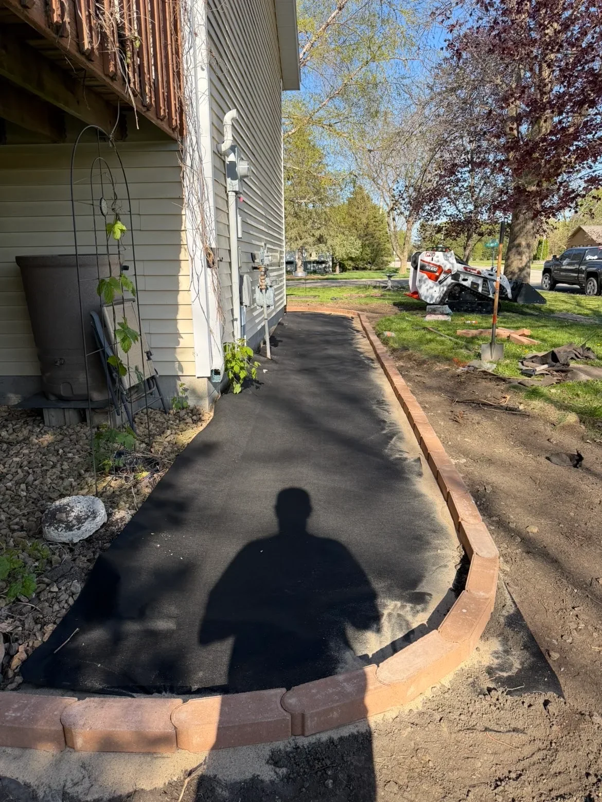 Asphalt walkway with brick edging along residential home foundation