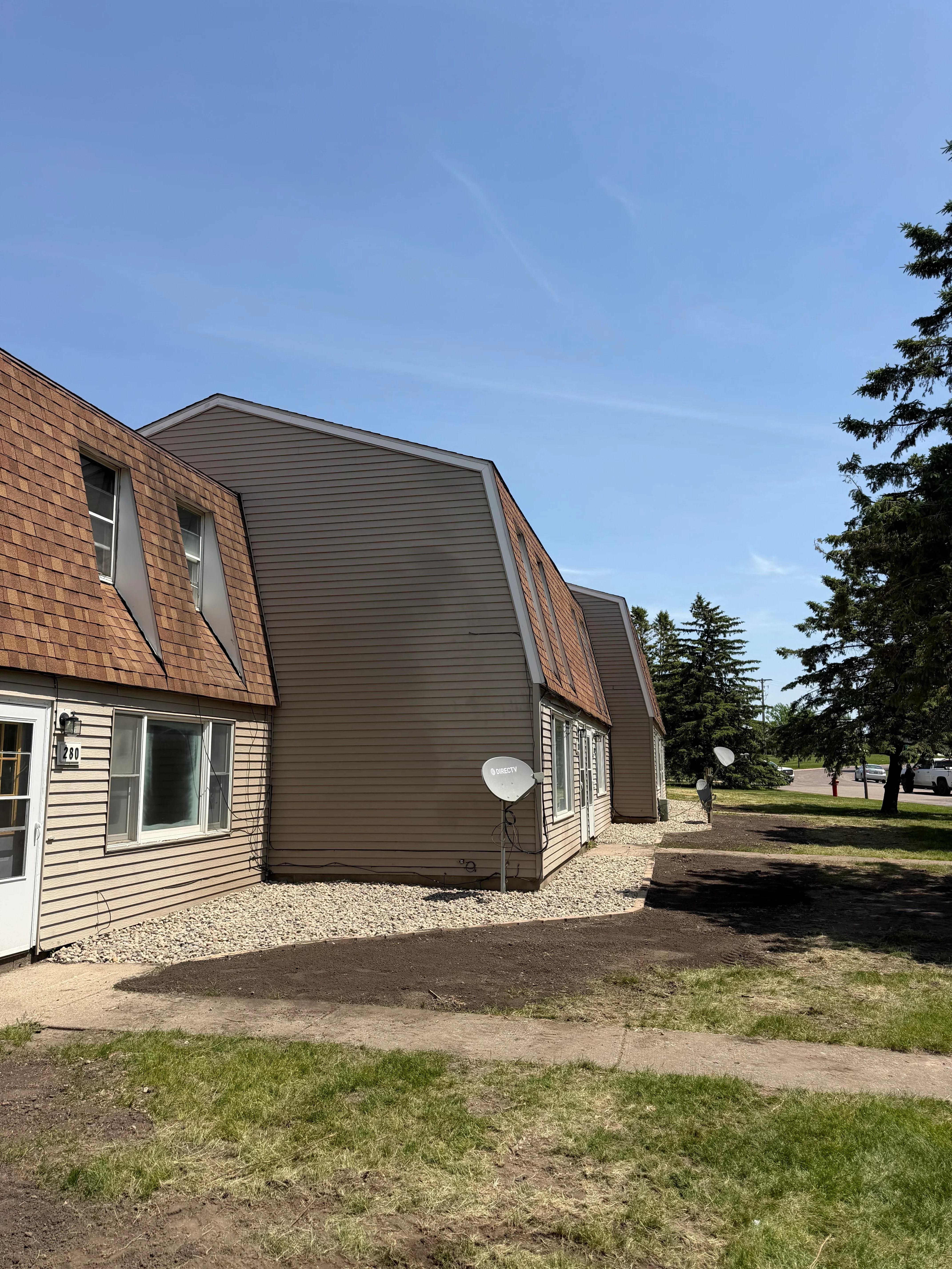 Residential property with graded lawn, planted beds, and corrugated metal structure